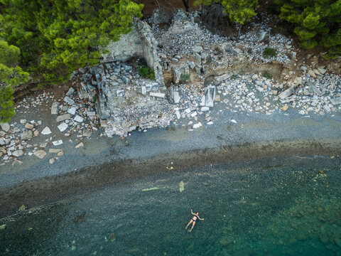 a woman is floating in the sea at the archeological site of Phaselis, turkey