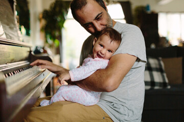Baby and dad playing piano at home