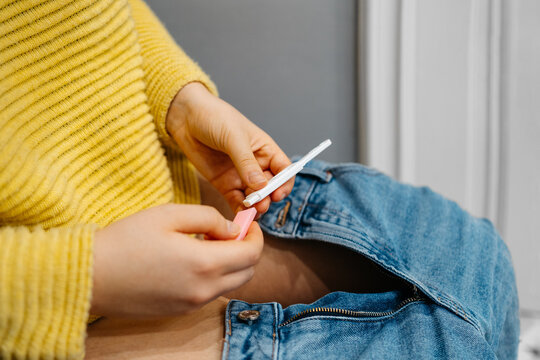 Side view of unrecognizable young woman taking pregnancy test at bathroom