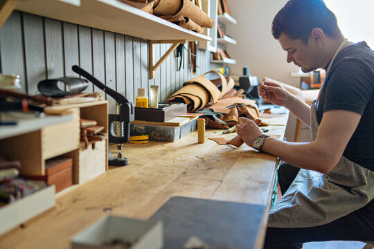 a man works at a workbench in his leather workshop