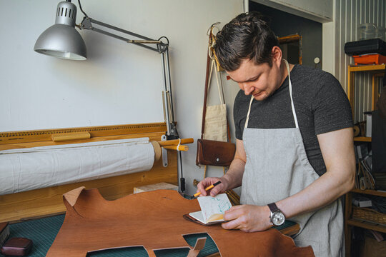 a craftsman in his workshop makes notes in a notebook