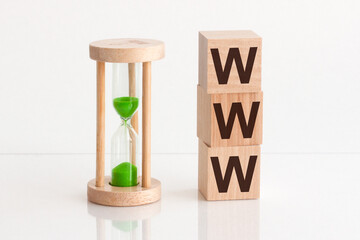 Close-up of an hourglass next to wooden blocks with the text WWW