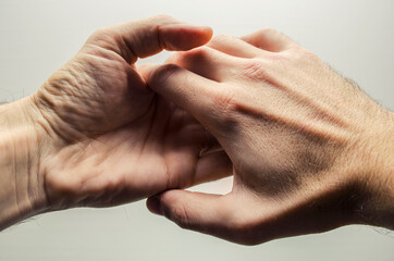 Fototapeta premium Men holding hands, hands on a light background, male friendship