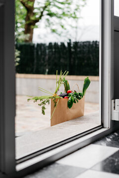 Delivery of groceries in a paper bag to house entrance