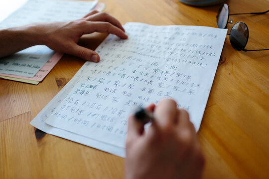 Anonymous hands writing Chinese characters on a paper
