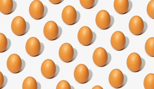 Seamless background of brown eggs placed in rows on white table in studio
