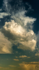 vertical panoramic view of a dramatic sky with cumulus clouds and warm lighting from below. Artistic creative background