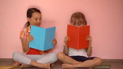 education and school concept - little student girls studying and reading book at home