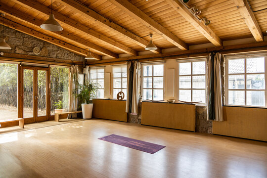 Yoga mat placed on wooden floor inside spacious pavilion decorated in oriental style located in tropical country