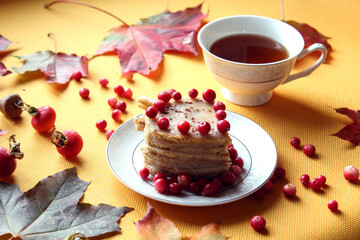 Puff pastry with cranberry berries on the background of a tea mug and autumn foliage, side view