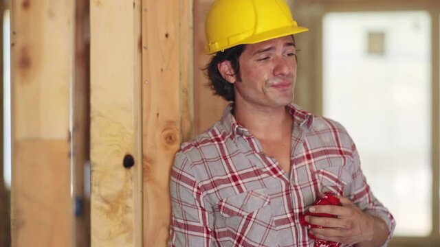 Overworked, tired and sick construction worker using his phone to call his doctor.