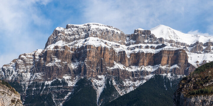 Spectacular landscape of mountain with snowy peak on slope under blue cloudy sky in sunny autumn day