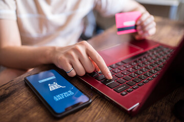 Female sitting at table at home and making payment for online purchases for food via mobile app