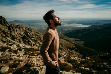 Side view of man standing on stone with eyes closed admiring Puerto de la Morcuera mountain range on cloudy day in Spain