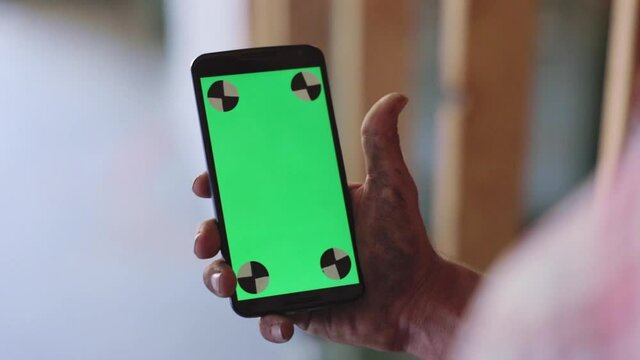 Over The Shoulder Shot Of A Construction Worker With Dirty Hands, Using His Phone To Call A Doctor, Chroma Green Screen.