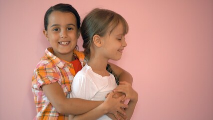 Two happy girls hugging each other isolated on pink background
