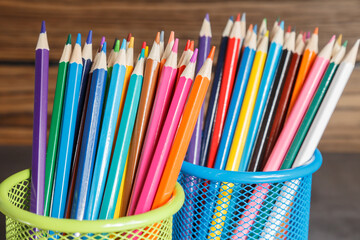 Fototapeta premium Pens and pencils in metal holder in front of wall background