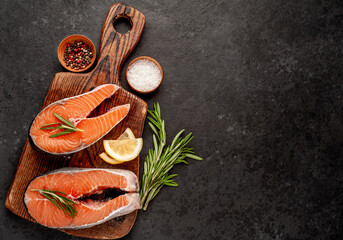  Raw fish salmon steak with lemon and rosemary on a stone background  with copy space with copy space