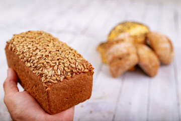 Dark bread with grains on the hand. Fresh bread in the bakery.