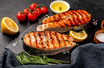 Grilled salmon steak with lemon and rosemary on a stone background	