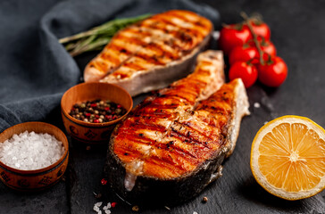 Grilled salmon steak with lemon and rosemary on a stone background	