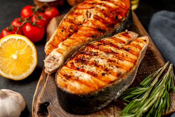 Grilled salmon steak with lemon and rosemary on a stone background