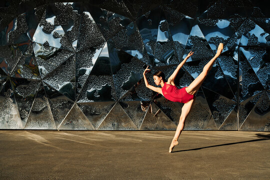 Portrait of young woman performing ballet dance on street against building