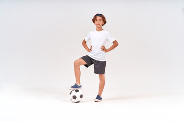Football player. Full-length shot of a happy teenage boy with soccer ball looking at camera and...