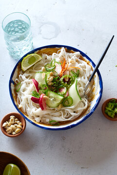 Top view of vegan rice noodle salad made with fresh vegetables, lime and peanut sauce