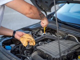 Hombre joven revisando el aceite del coche