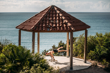 Side view of strong sportsman balancing on parallel bars in handstand during workout on sunny day in summer