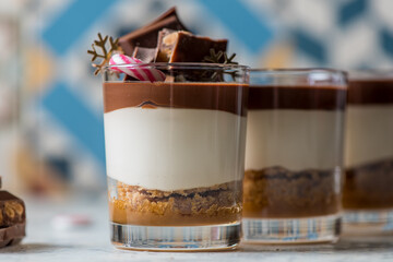 Yummy vanilla and chocolate dessert in glass cup decorated with Christmas items