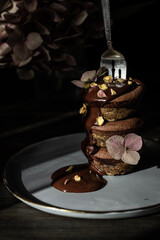 Stack of three chocolate and matcha cupcakes poured with dark chocolate with vintage silver fork in it on dark background.