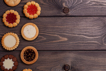 shortbread cookies with various fillings on a brown wooden table. Top view, copy location. Bakery,