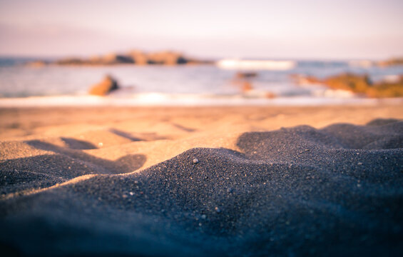 Ground level closeup of sandy shore on background of sea at amazing sundown in summer