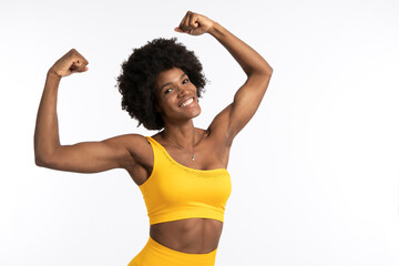 Black female in yellow sportswear posing and looking away against gray background