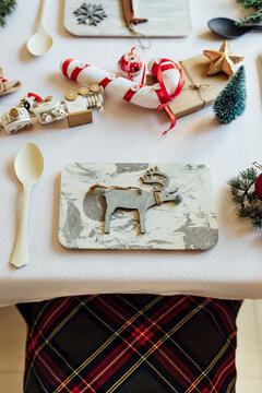 From above of festive table decorated with various Christmas elements and toys arranged near utensils for kids celebration