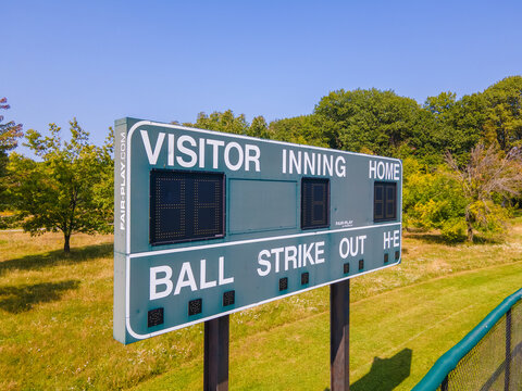 Old Baseball Scoreboard In Wooded Field With Fence.