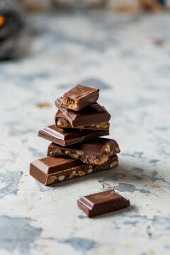 Closeup of stacked broken pieces of chocolate bar with nuts placed on table