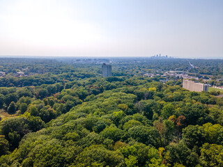 Aerial view of building in trees with downtown skyline in the background