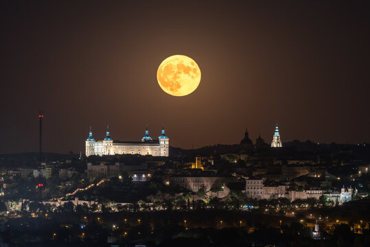 Amazing view of bright full moon in dark night sky over old town with glowing historical palace