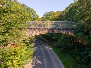 Fototapeta premium Old stone pedestrian bridge in woods with leaves just starting to change color