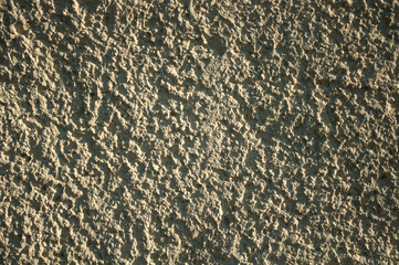 Grainy background,  light yellow wall surface texture shot on a sunny day, hard shadows