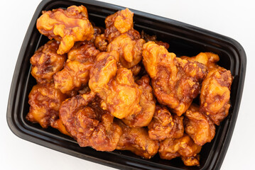 Overhead view of large bowl of orange flavored chicken shows the sheen of sweet sauce and meat