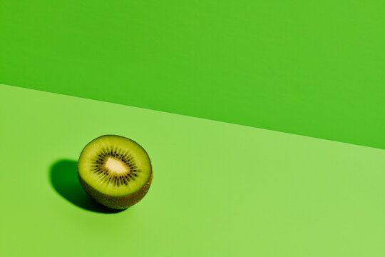 Half of delicious ripe kiwi fruit placed on green background in modern studio