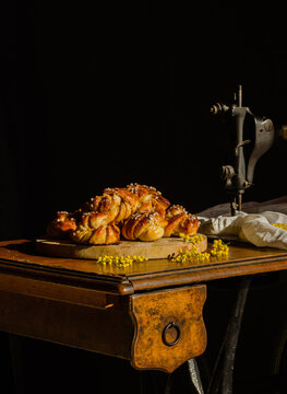 Pile of delicious Swedish cardamom buns placed on cutting board on rustic table with sewing machine
