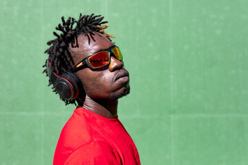 Side view of serious African American male athlete listening to music in headphones while preparing for training in summer