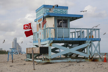 blue lifeguard tower with red flag on the sand beach