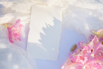 Blank paper card with copy space . Pink gladiolus flower on white textile background. Styled stock photography for display your design, lettering, font, illustration, wedding stationary. Flat lay