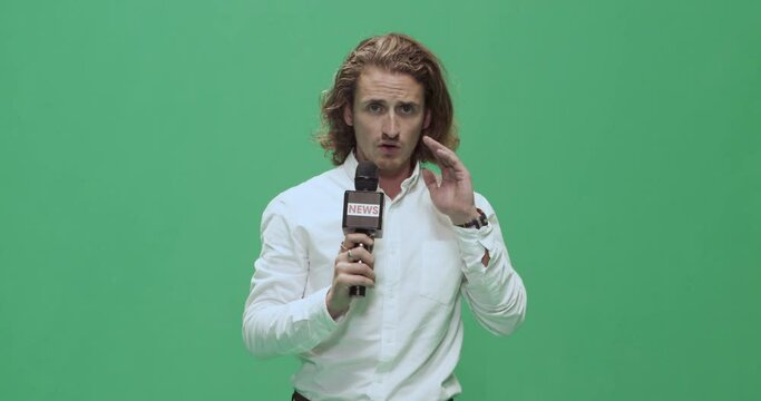 Studio, slow motion, green screen, young male reporter listens to his earpiece, London, UK